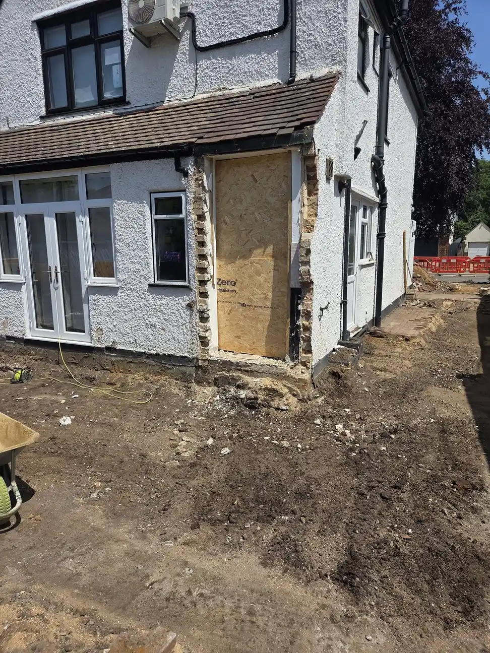 Excavation work beside a house during property groundworks.